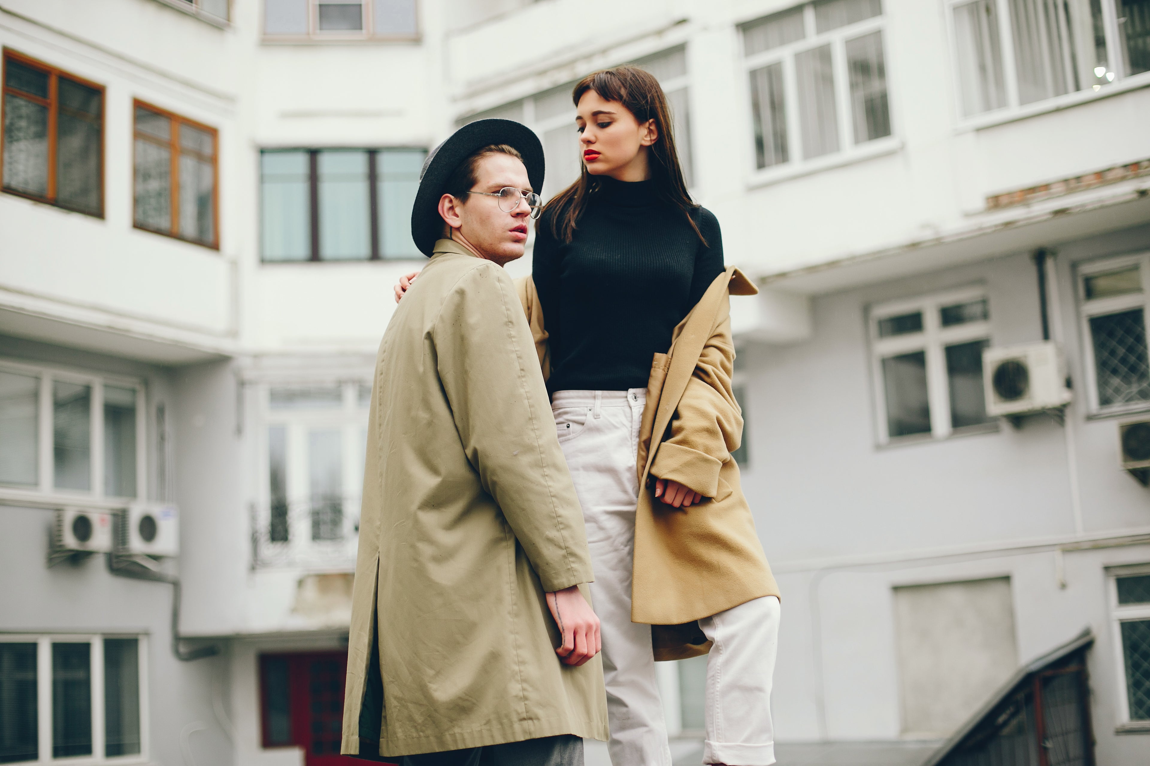 Two people standing close together in an urban setting with a building in the background.